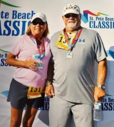 Burton and Julie, an older white couple in sunglasses and baseball hats wearing medals around their necks after completing a 5K walk. Burton, standing on the right, had undergone the Vertiflex Procedure two months earlier to treat disabling back pain.