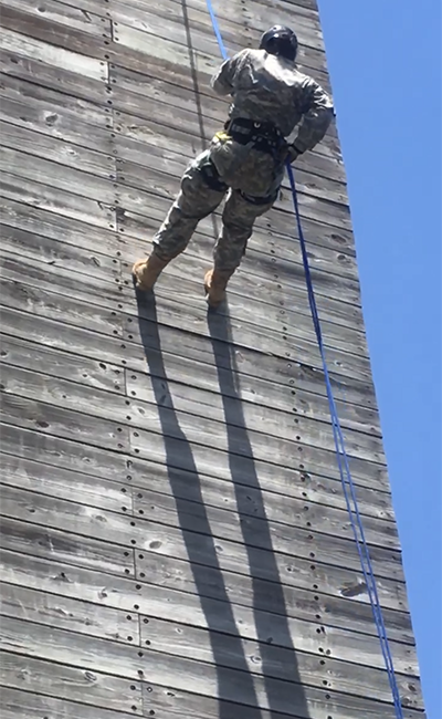 Caroline climbs down a wall wearing Army fatigues, in a photo taken before she developed chronic pain